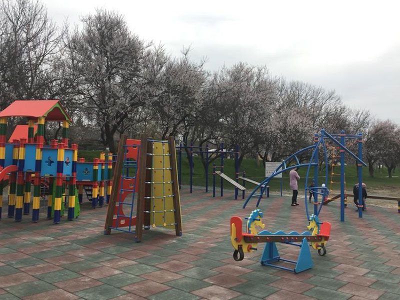 Родители гуляют с детьми на площадке